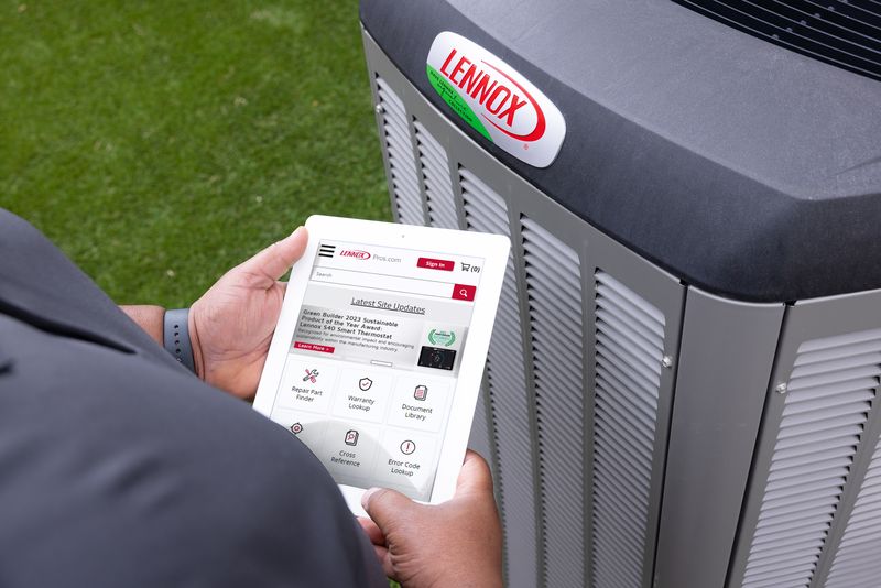 Technician holding a tablet next to a Lennox outdoor unit
